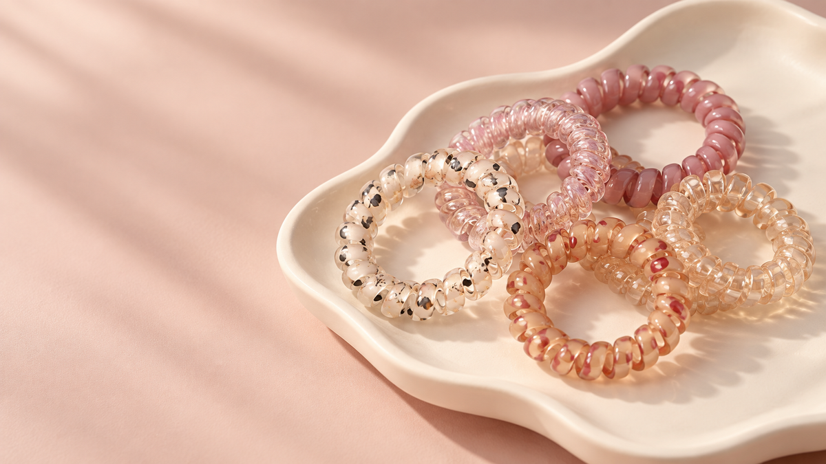Illustrative image of five blush and champagne spiral hair ties on an ivory tray